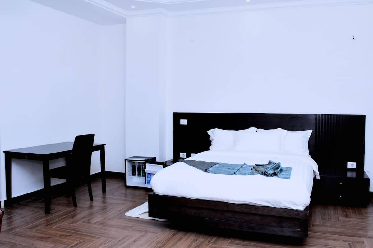 A modern bedroom with a bed, a desk, and a nightstand.