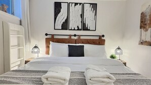 A neatly made bed with a striped blanket, two bedside lamps, and artwork above the bed.