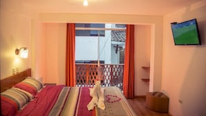 A hotel room with a bed, a TV on the wall, and a balcony with a view. - Sol de los Andes Machupicchu (Machu Picchu)