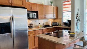 Une cuisine moderne avec des meubles en bois, des appareils en acier inoxydable et un plan de travail en granit.
