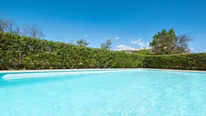 A clear blue swimming pool surrounded by lush greenery and a clear sky. - Elegant Apartment near the Beach (Alvor)
