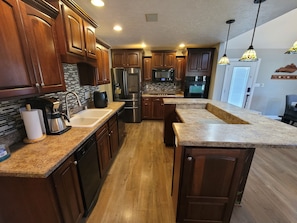 A kitchen with wooden cabinets, granite countertops, stainless steel appliances, and pendant lighting. - Large Private Home close to Bourbon Trail!/POOL/Free Firewood/Parks/Close to I65 (Shepherdsville)