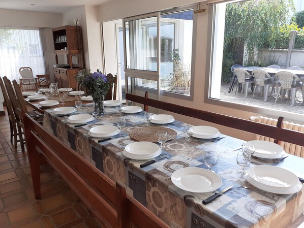 A long dining table set with plates, glasses, and cutlery, flanked by chairs.