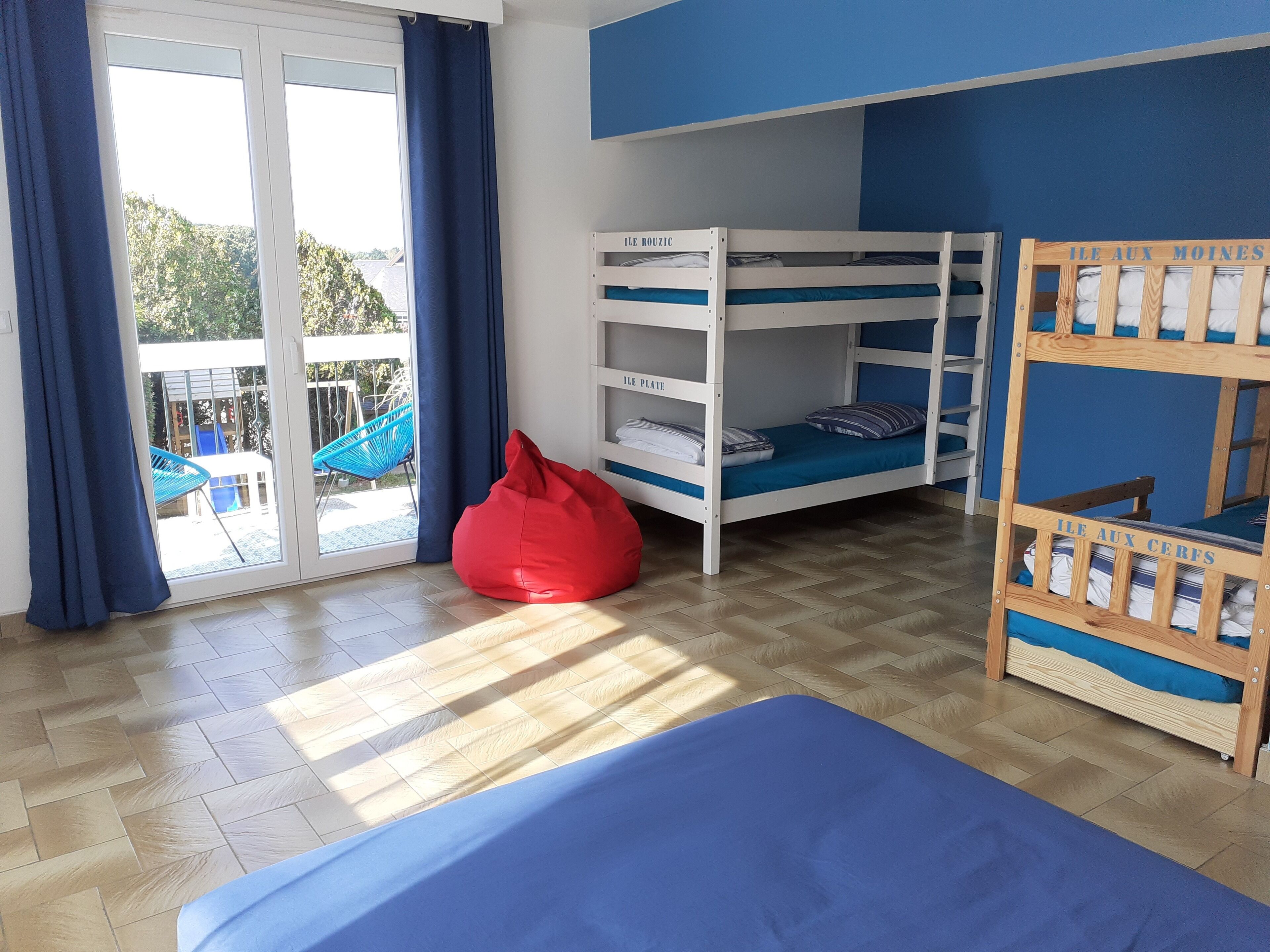 Ein Zimmer mit Etagenbett, Sitzsack und einer Schiebetür zu einem Außenbereich.