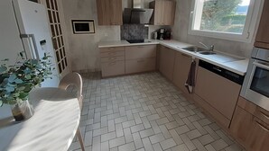 Eine moderne Küche mit Fischgrätparkett, Holzschränken, einem eingebauten Backofen und einem Fenster, das für natürliches Licht sorgt.