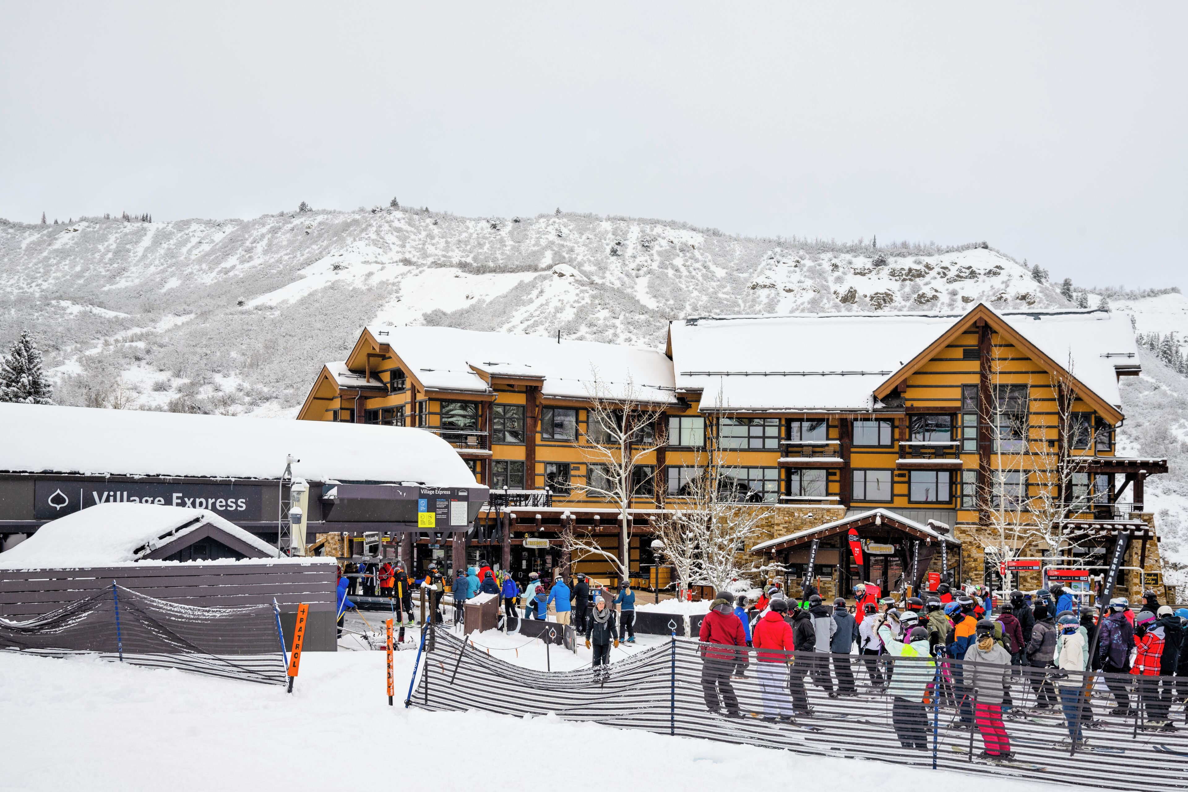 A lodge with multiple stories and a ski lift in the background.
