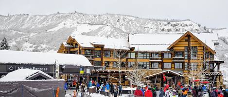 A lodge with multiple stories and a ski lift in the background.