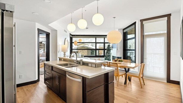 Una cocina moderna con una isla central, electrodomésticos de acero inoxidable e iluminación colgante.