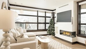 Una sala de estar moderna con chimenea, un sofá, una mesa de centro y un árbol de Navidad.