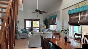 A spacious living area with a wooden dining table, grey sofas, and a ceiling fan. - 10% OFF ON STAYS OF 7 NIGHTS OR MORE ! AMAZING BEACHFRONT PROPERTY.. (San Pedro)
