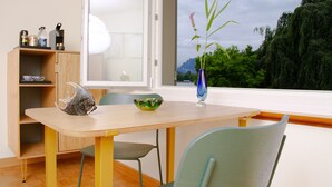 A room with a wooden table, a blue vase with a plant, a green chair, and a wooden cabinet with shelves. - Villa Maria (Lucerne)