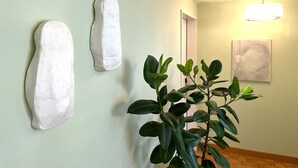 A hallway with three white wall art pieces and a potted plant. - Villa Maria (Lucerne)