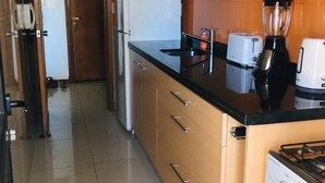 A kitchen with wooden cabinets, a microwave, a blender, a toaster, and a refrigerator.