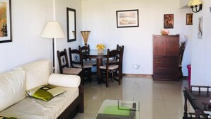 A living room with a sofa, a coffee table, a dining table with chairs, and a cabinet.