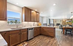 A kitchen with wooden cabinets, a dishwasher, and a large window overlooking a scenic view.