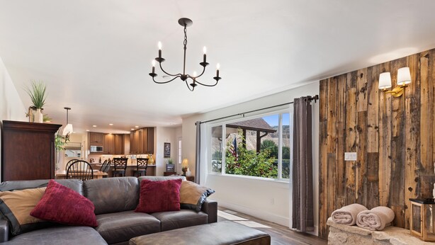 Uma sala de estar ampla com sofá modular, parede de destaque em madeira e uma grande janela com vista para o exterior.