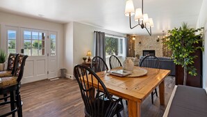 Uma sala de jantar com mesa e cadeiras de madeira, um candelabro e vista para o exterior.