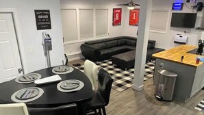Een moderne keuken met een bar, een eettafel met stoelen, een zwarte leren bank en een zwart-wit geruit vloerkleed.