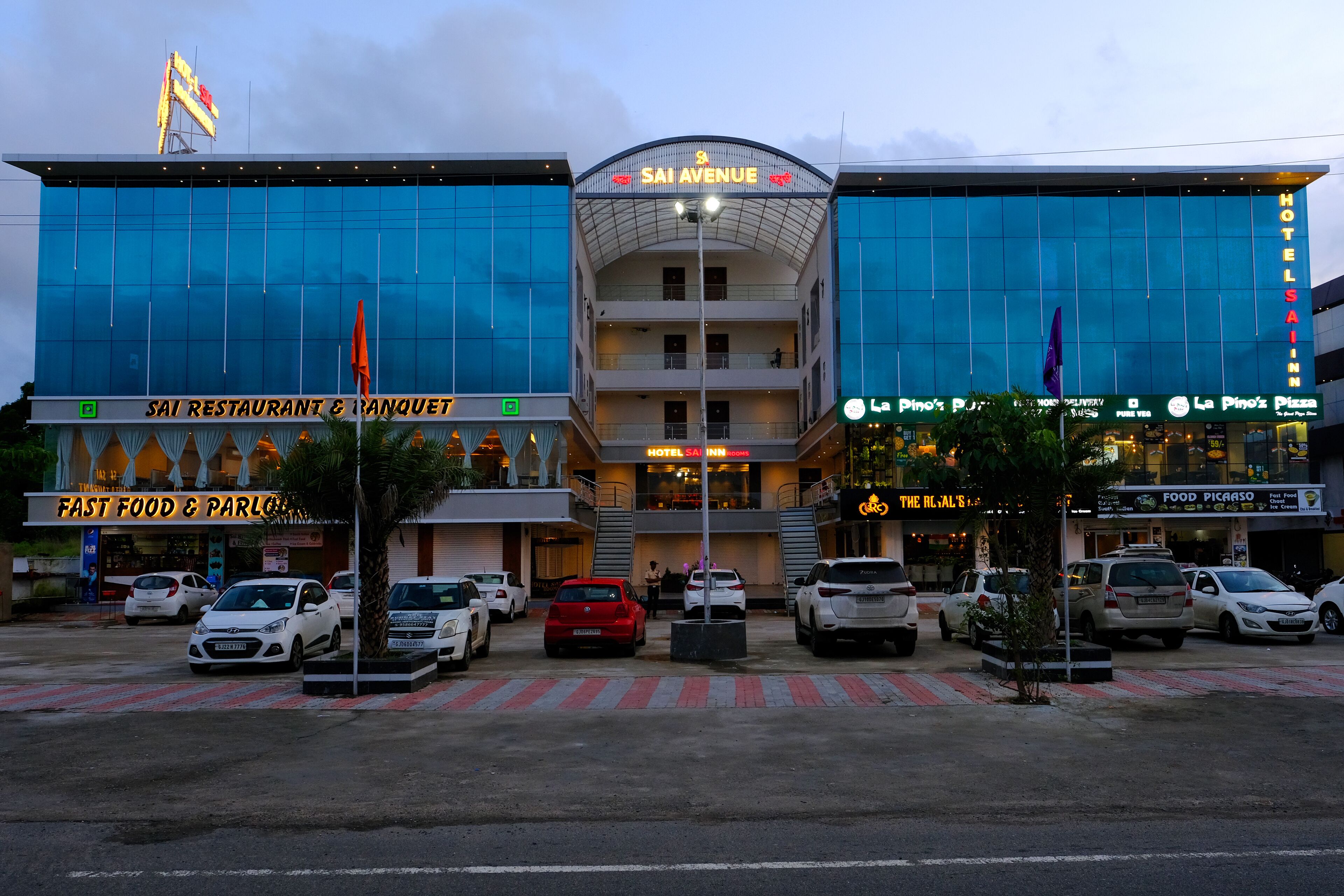 A hotel with a modern glass facade, multiple floors, and a prominent sign reading "SAI AVENUE HOTEL".