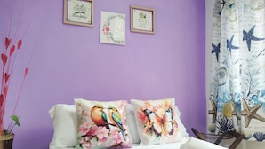 Ein Schlafzimmer mit roter Bettdecke, zwei Kissen mit floralem Muster und einer Wand mit drei gerahmten Motivationssprüchen.