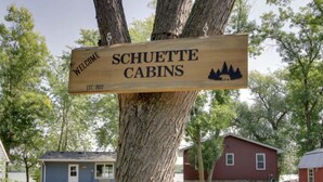 A wooden welcome sign for Schuette Cabins with a cabin illustration and establishment year.