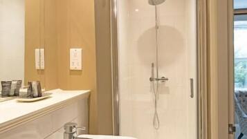 Une salle de bain moderne avec une douche à parois de verre, un lavabo blanc et un miroir au-dessus.