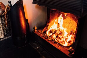 A fireplace with visible flames, a metal container, and a woven basket.