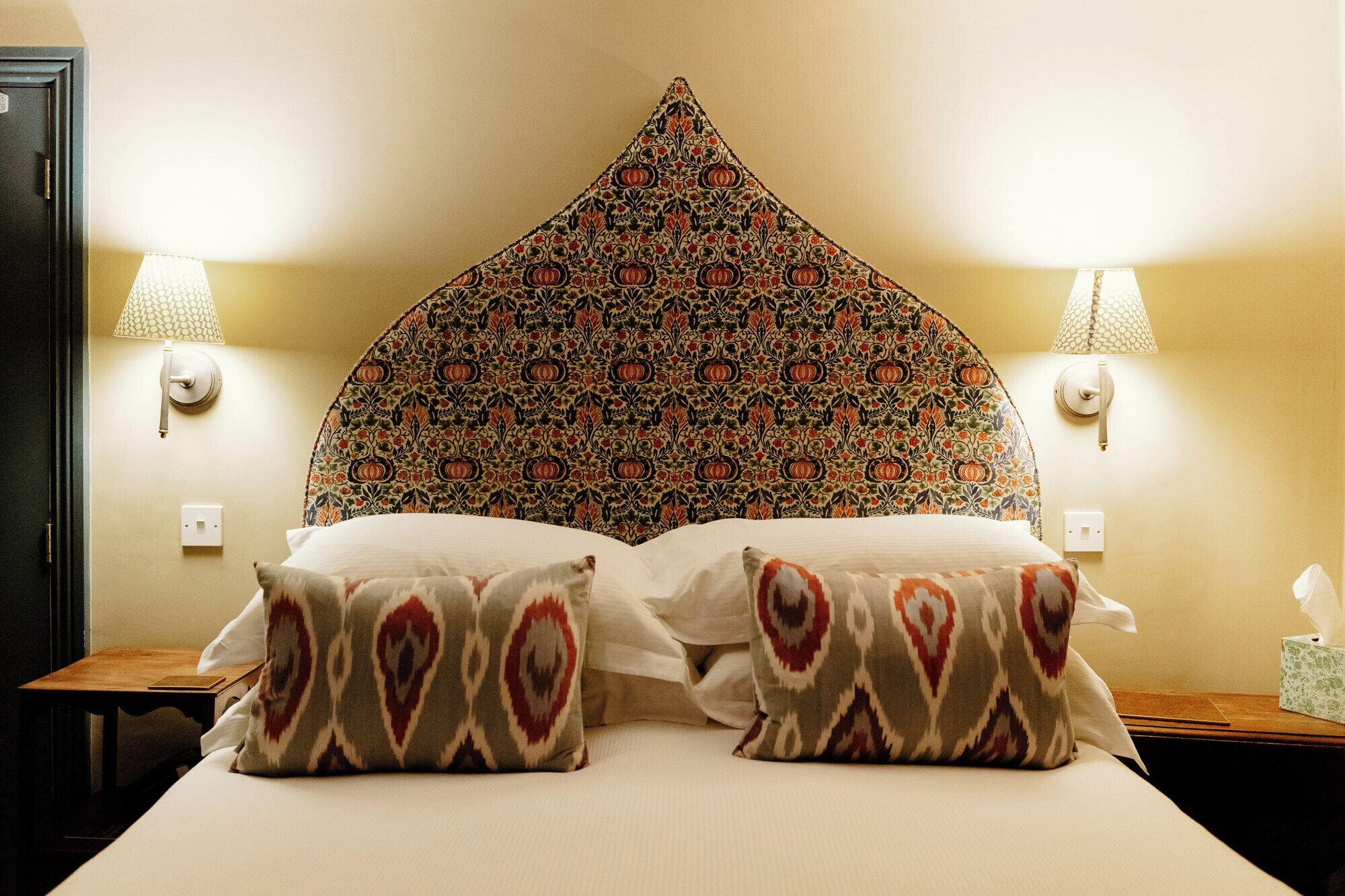 Ein Hotelzimmer mit einem großen Bett, zwei Nachttischlampen und einem gemusterten Kopfteil.