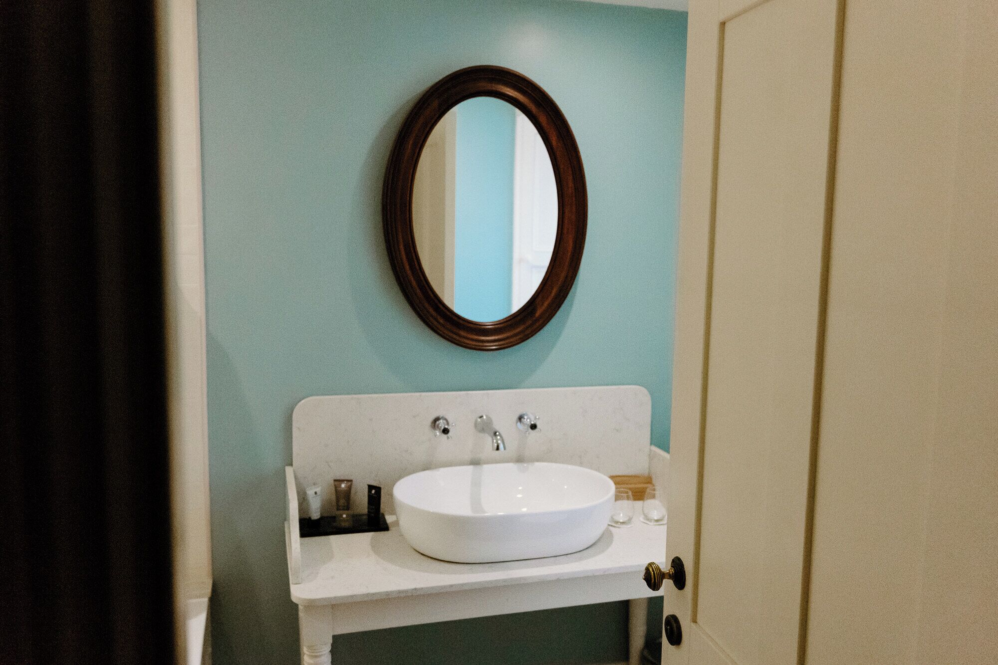 A bathroom with a white sink, a mirror, and a door.