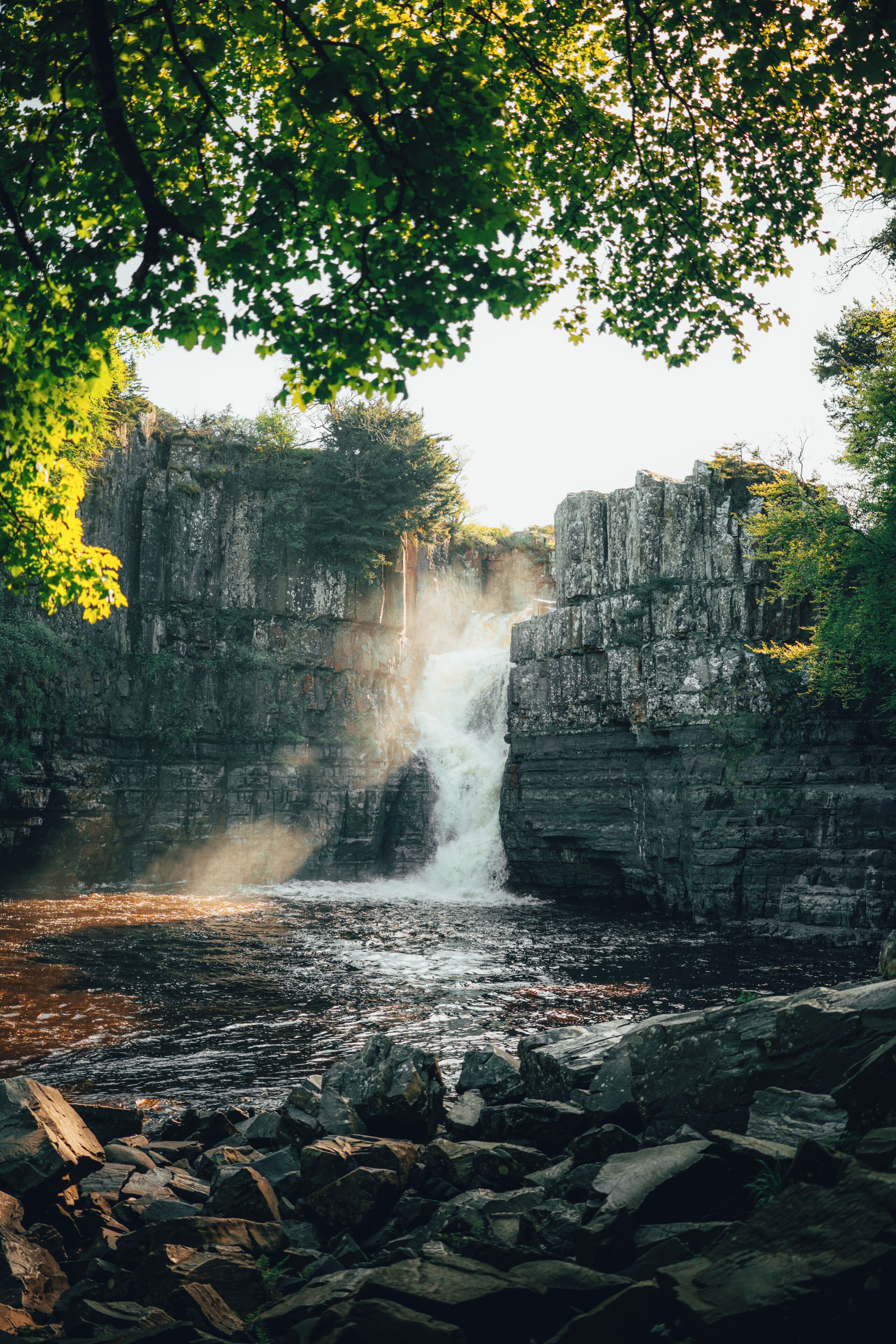 A waterfall cascading over rocky cliffs surrounded by dense foliage.
