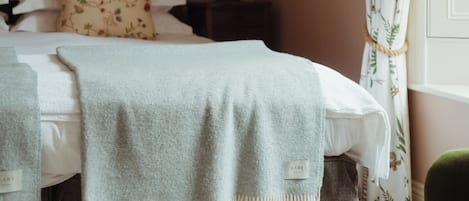 A neatly made bed with a headboard, a bedside lamp, and a floral pillow.