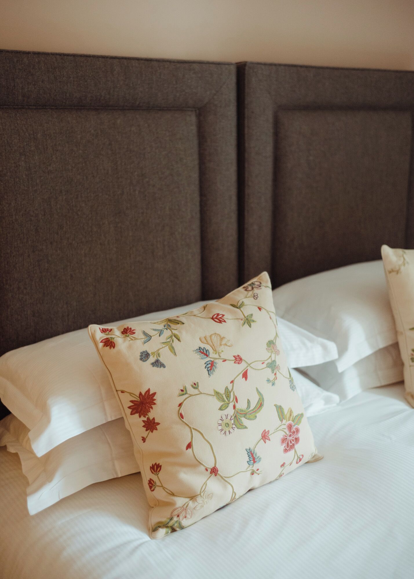 Un lit avec un oreiller à motifs floraux et une tête de lit.