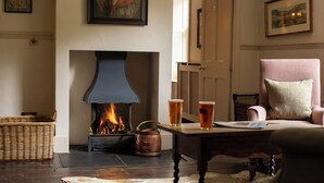 Una habitación acogedora con chimenea, una mesa con vasos y una silla.