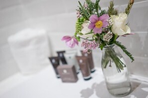 Een glazen vaas gevuld met een boeket bloemen op een witte ondergrond.