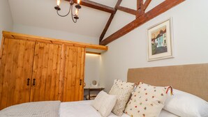 Quarto com guarda-roupa de madeira, cama com roupa de cama branca e um candelabro.