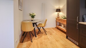 Uma cozinha compacta com uma mesa de jantar, cadeiras, um armário e uma televisão fixada na parede.