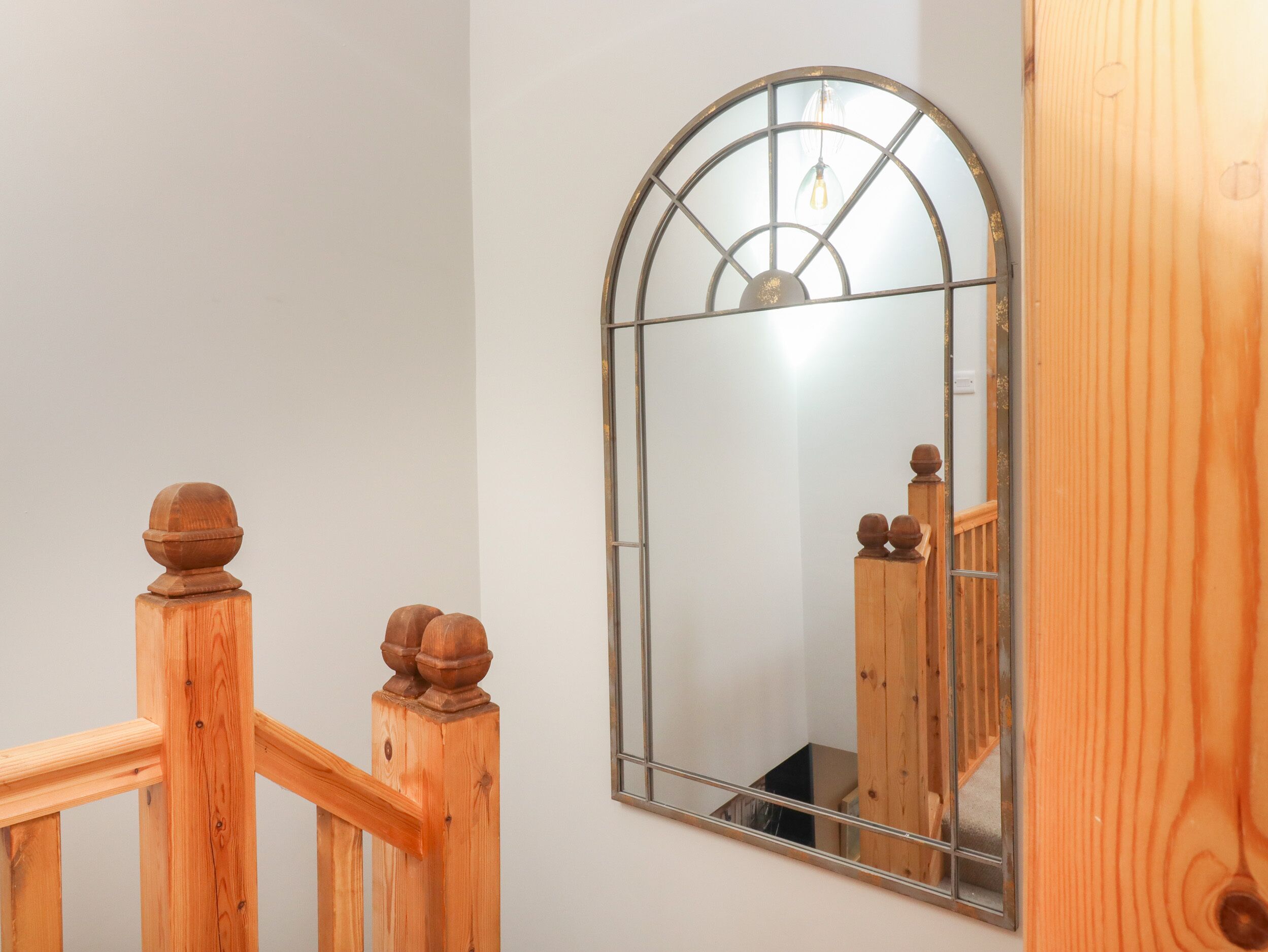 A wooden staircase with a glass door and a mirror reflecting the interior.