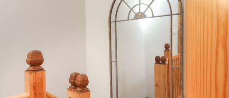 A wooden staircase with a glass door and a mirror reflecting the interior.