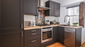 Uma cozinha moderna com armários escuros, micro-ondas, fogão e lava-louças.