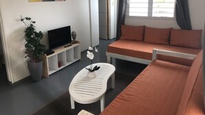 Un saló modern amb un sofà, un televisor, una taula de centre i una planta en test.