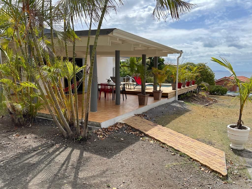 Un espacio al aire libre techado con piscina, mobiliario y plantas en macetas.
