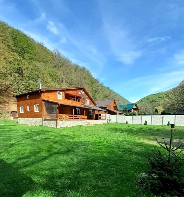 A large wooden house with a stone foundation, multiple windows, and a covered porch. - Valea Tonii B&B Strungari (Strungari)