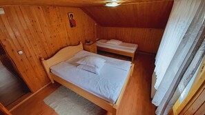 A wooden-paneled room with two beds, a small dresser, and a ceiling fan. - Valea Tonii B&B Strungari (Strungari)