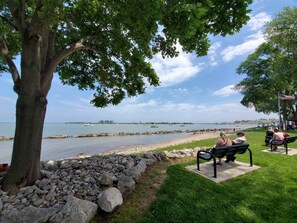 A park with a large tree, a rocky shoreline, and a view of the water. - Large home with yard, 7 bedrooms, and lots of living space (Huron)