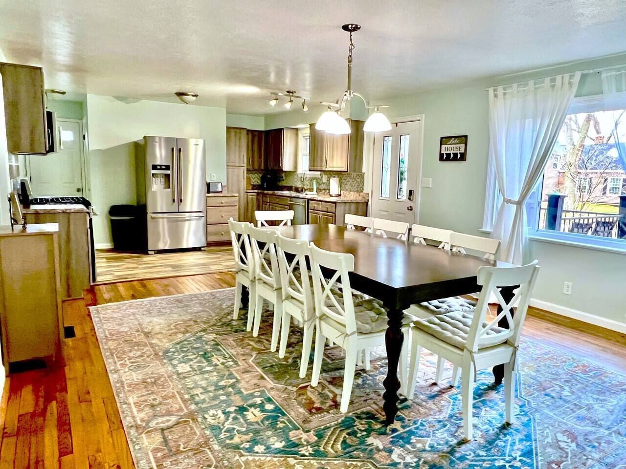 A spacious kitchen with modern appliances, a dining area with a large table and chairs, and a view through a window.
