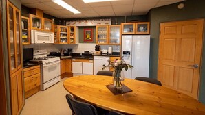 A kitchen with wooden cabinets, a white stove, and a dining table with chairs.
