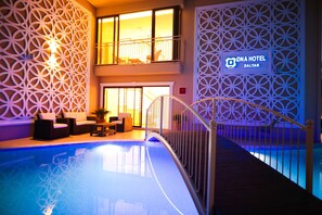 An indoor swimming pool with a geometric wall design, a lounge area with seating, and a sign for DNA Hotel Dalian. - Dna Hotel Dalyan Adult Only (Ortaca)