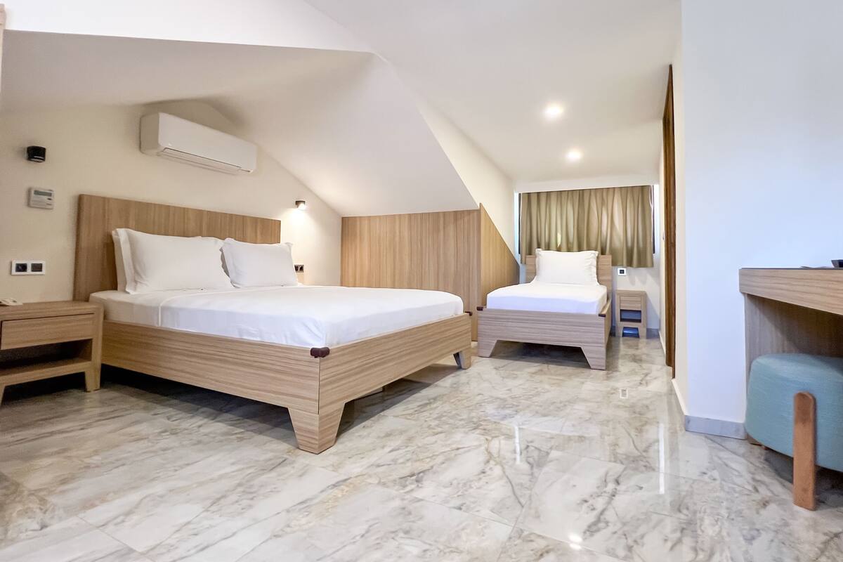 A modern hotel room with two beds, a desk, and a vanity.