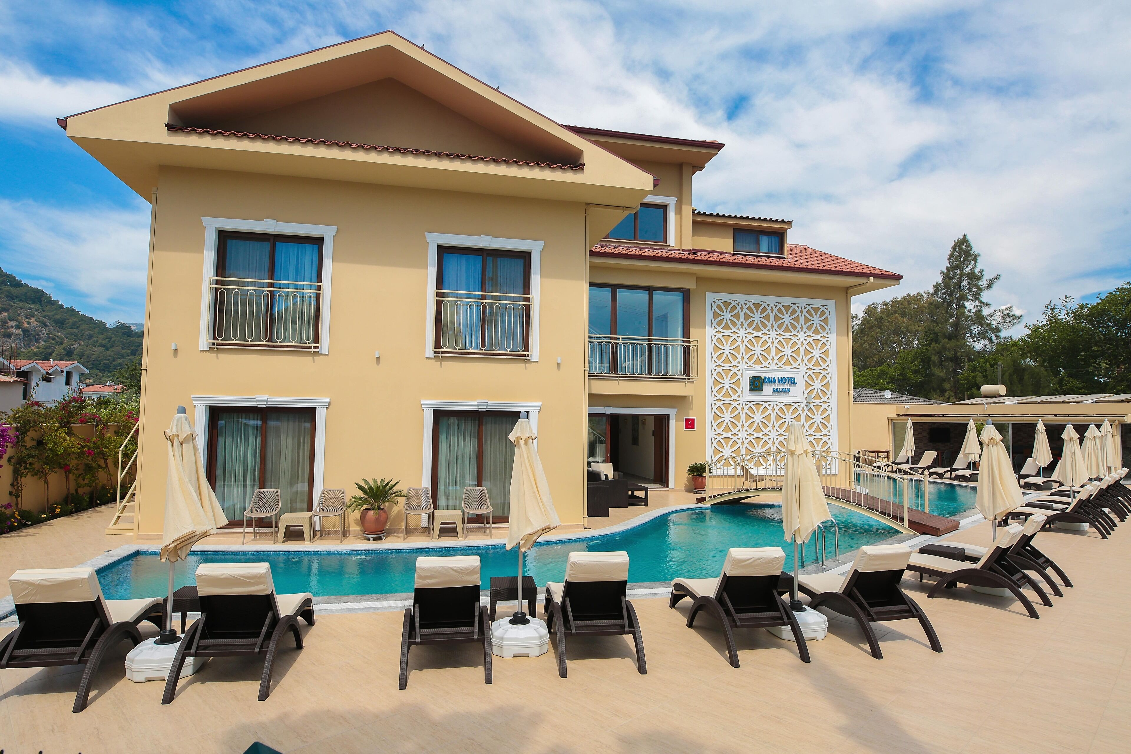 A hotel with a pool, multiple lounge chairs, and a mountain backdrop.