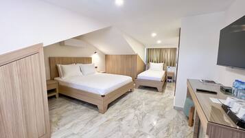 A hotel room with two beds, a desk, a TV, and a minibar.